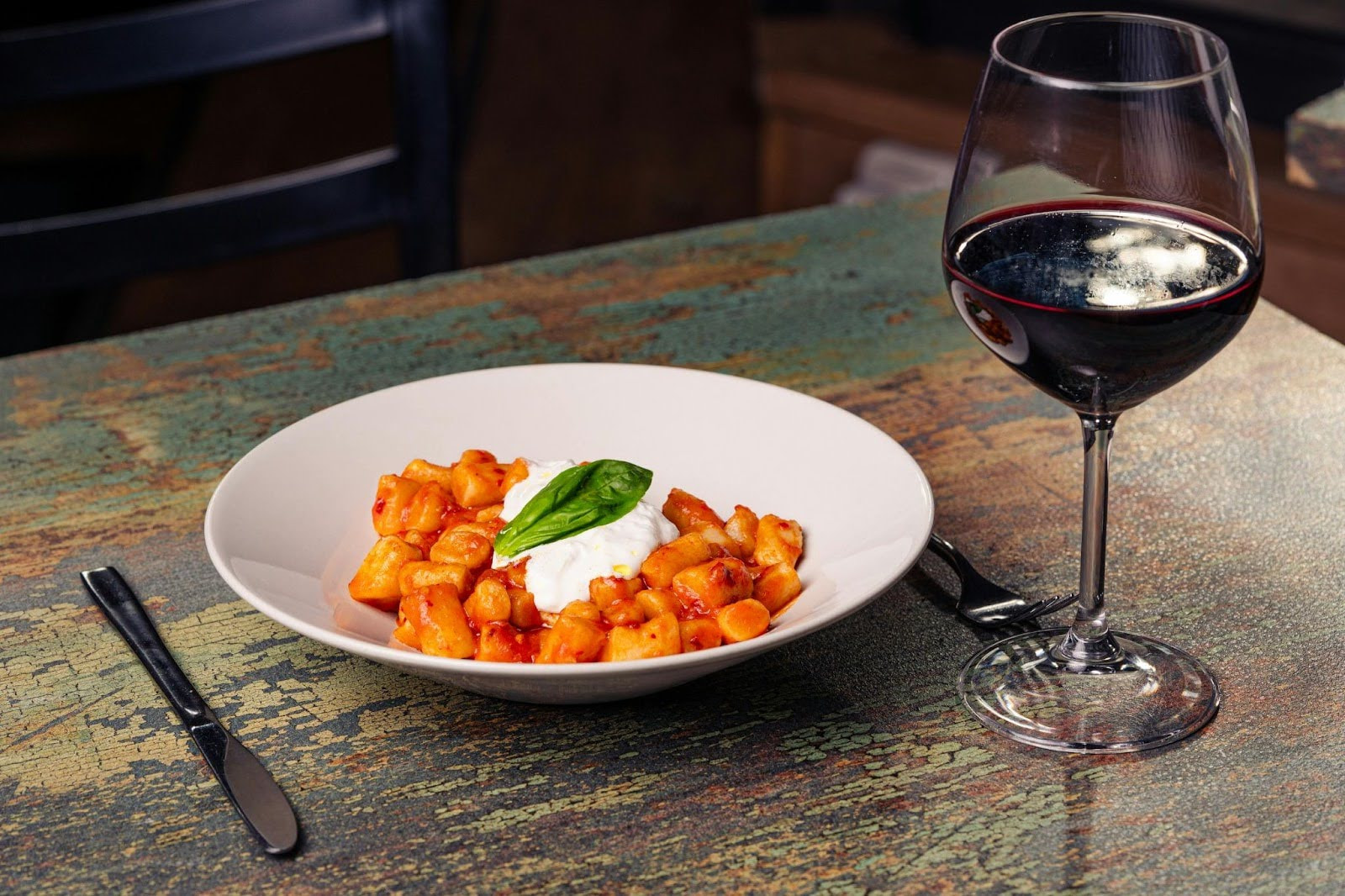 Plate of gnocchi with tomato sauce and burrata, paired with red wine.